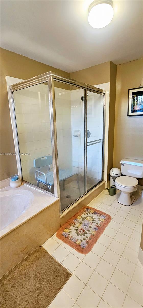 bathroom with tile patterned flooring, toilet, and independent shower and bath