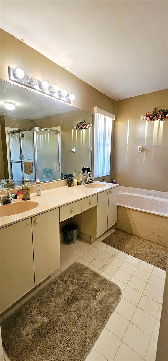 bathroom with tile patterned flooring, vanity, and shower with separate bathtub