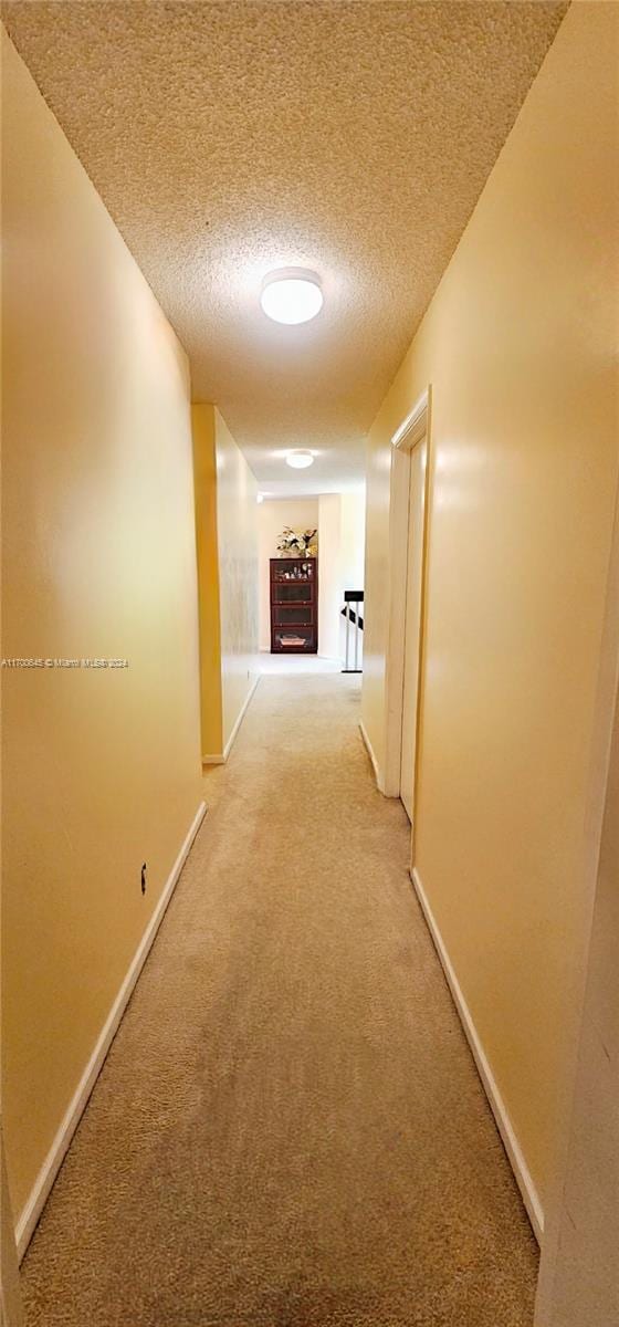 corridor featuring carpet floors and a textured ceiling