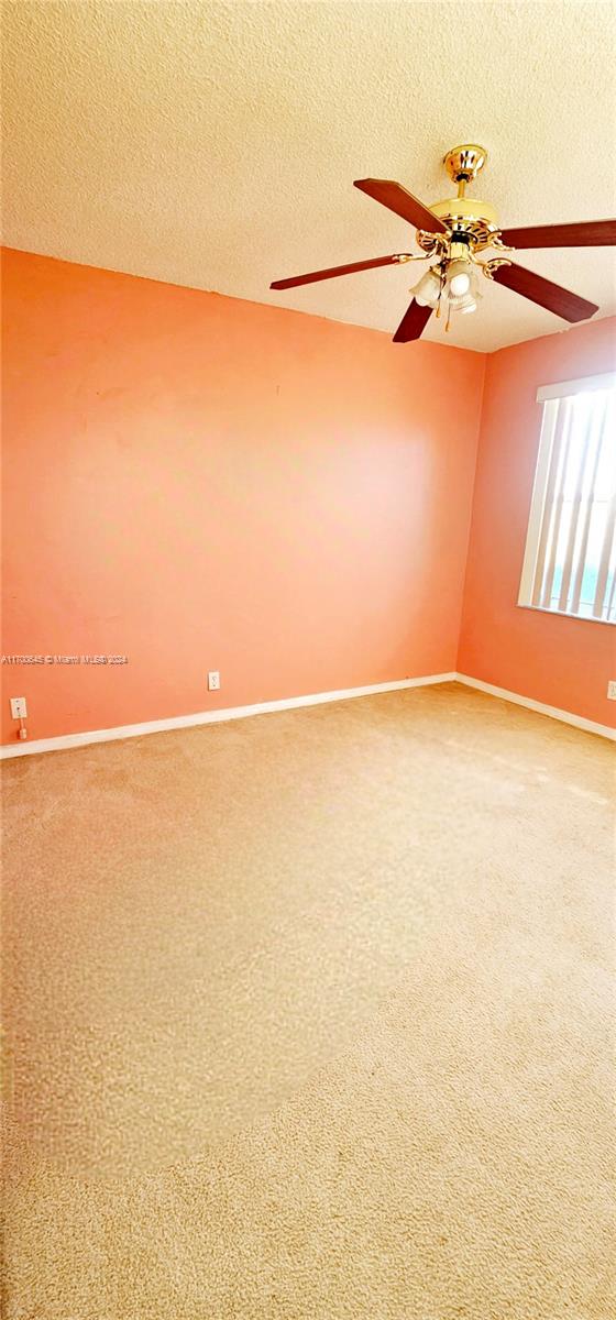 carpeted spare room with a textured ceiling and ceiling fan