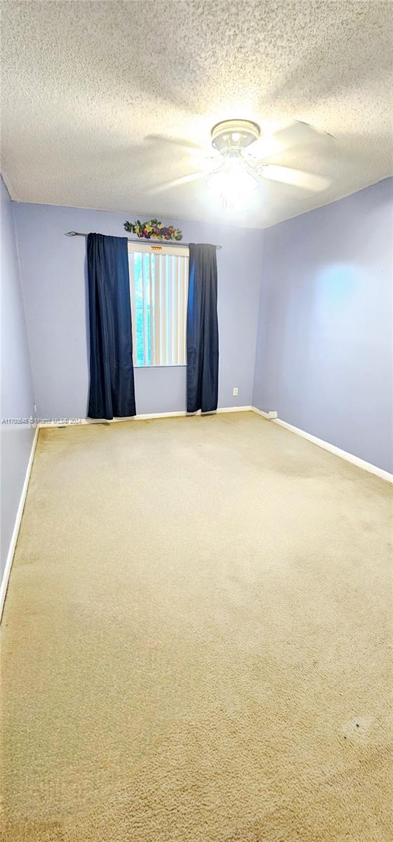 empty room with carpet flooring, a textured ceiling, and ceiling fan