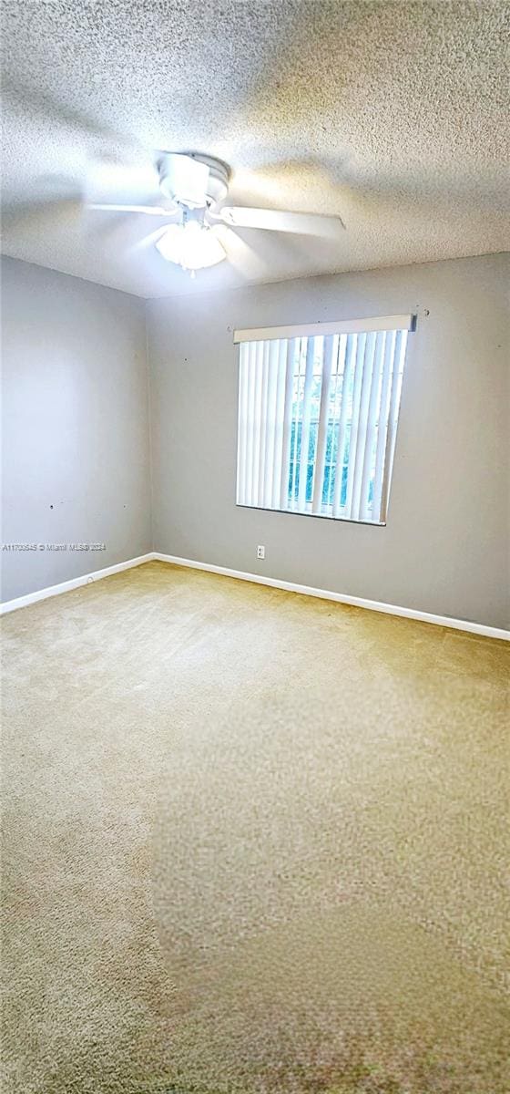 unfurnished room featuring ceiling fan, carpet floors, and a textured ceiling