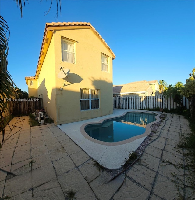 back of property with a patio and a fenced in pool