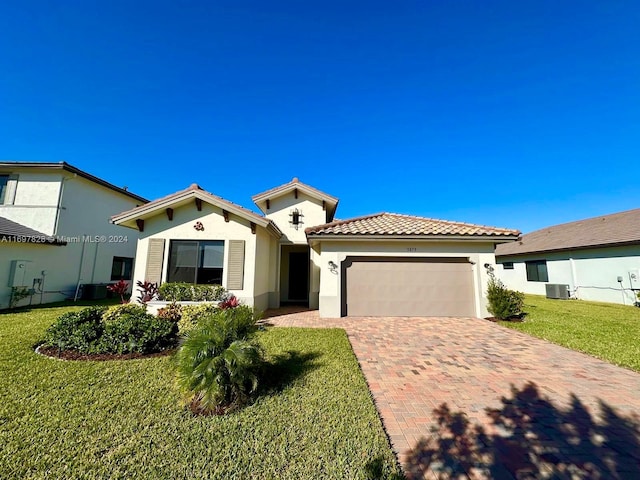 mediterranean / spanish home featuring central AC unit, a garage, and a front lawn