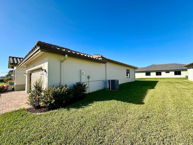 view of side of property featuring central air condition unit, a yard, and a garage