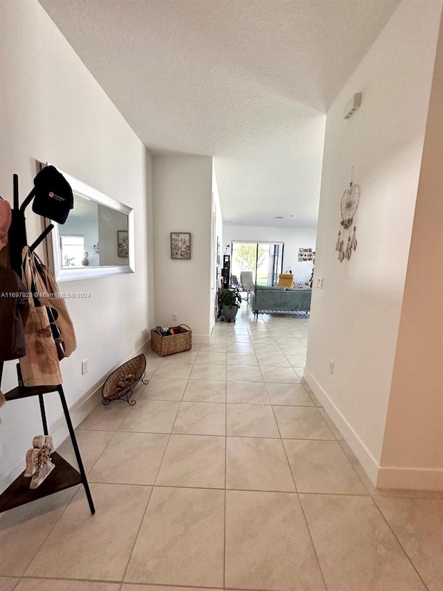 hall featuring light tile patterned floors and a textured ceiling