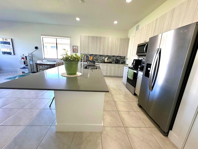 kitchen featuring appliances with stainless steel finishes, tasteful backsplash, sink, light tile patterned floors, and a center island with sink