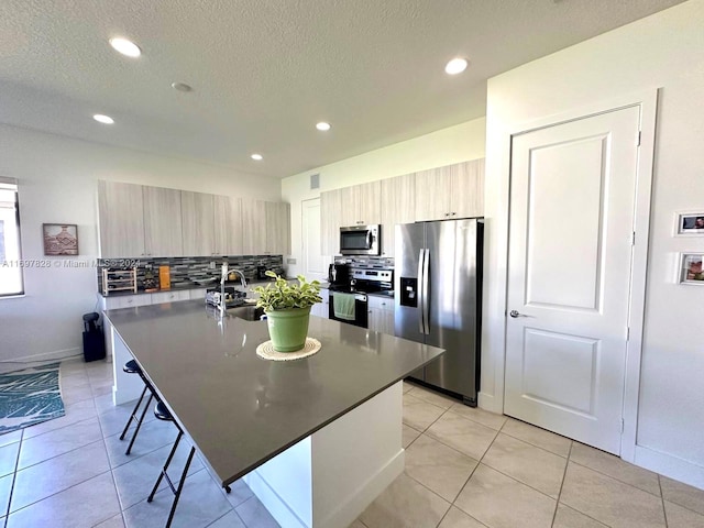 kitchen featuring a kitchen bar, backsplash, stainless steel appliances, sink, and a kitchen island