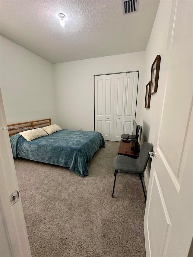 carpeted bedroom featuring a textured ceiling and a closet