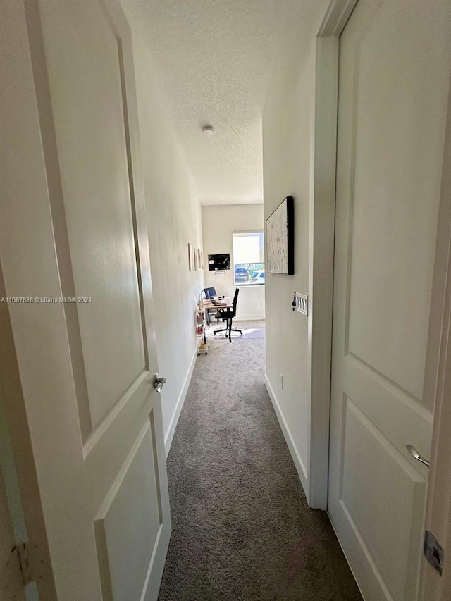 hallway with carpet and a textured ceiling