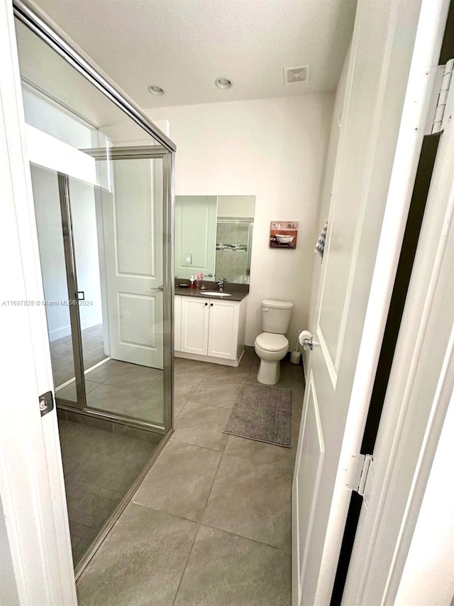 bathroom featuring a textured ceiling, vanity, toilet, and walk in shower