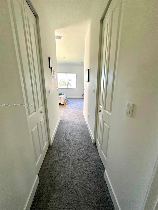 corridor with carpet flooring and a textured ceiling