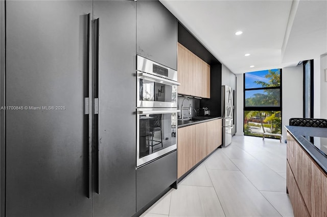 kitchen featuring sink, light tile patterned floors, stainless steel appliances, and expansive windows