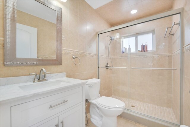 bathroom featuring vanity, tile patterned floors, toilet, tile walls, and walk in shower