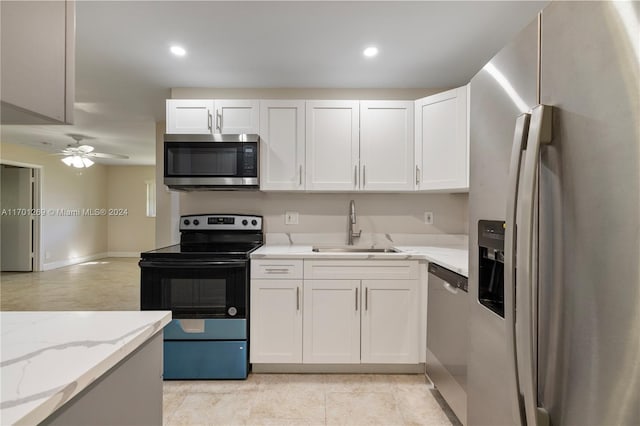 kitchen featuring light stone countertops, appliances with stainless steel finishes, ceiling fan, sink, and white cabinetry