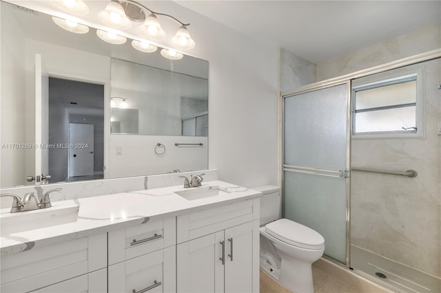 bathroom with toilet, vanity, tile patterned floors, and a shower with shower door