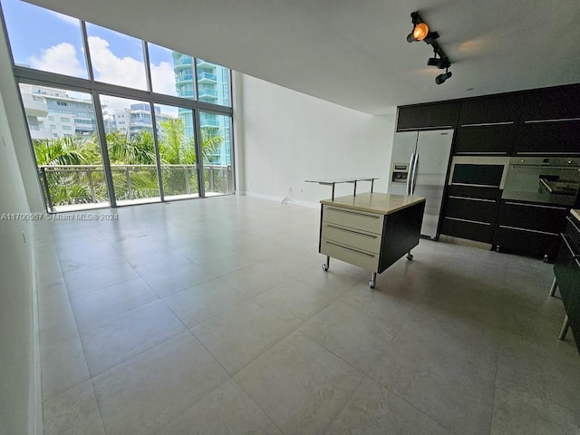 kitchen featuring stainless steel refrigerator with ice dispenser, a kitchen island, and floor to ceiling windows