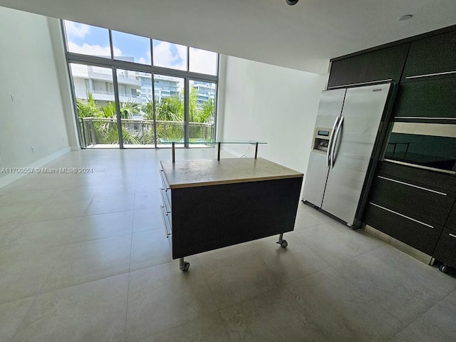 kitchen with stainless steel fridge, a kitchen island, and a wall of windows