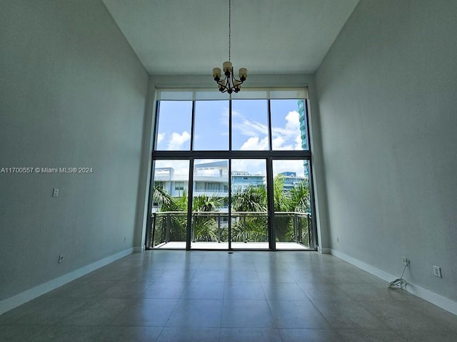 unfurnished room with a notable chandelier, expansive windows, and a high ceiling