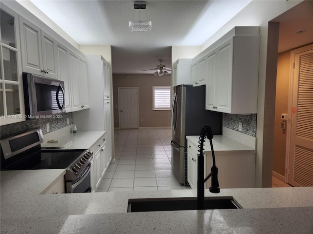 kitchen featuring appliances with stainless steel finishes, white cabinets, sink, backsplash, and light tile patterned flooring