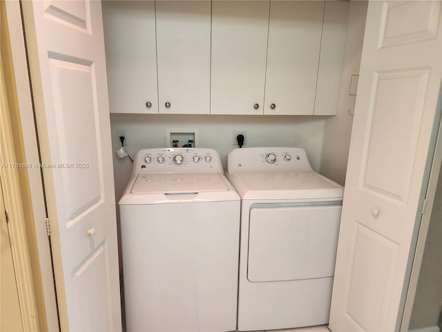 clothes washing area with cabinets and washing machine and clothes dryer