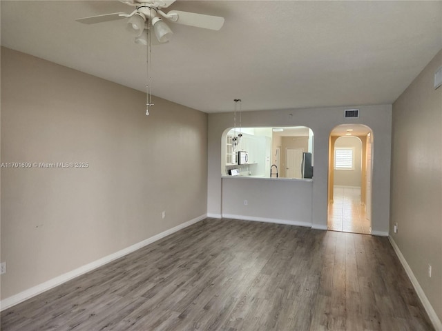 spare room with sink, ceiling fan, and wood-type flooring