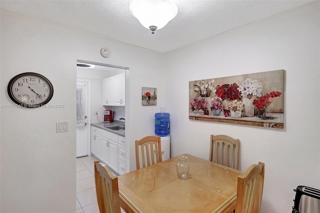 dining room with sink, light tile patterned floors, and a textured ceiling