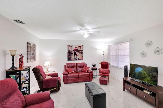 living room featuring ceiling fan, light tile patterned floors, and a textured ceiling