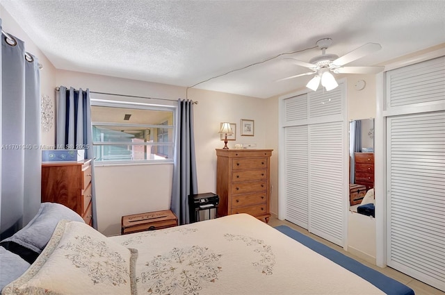 bedroom featuring ceiling fan, two closets, and a textured ceiling