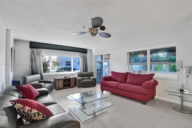 living room with a textured ceiling, ceiling fan, and light tile patterned flooring