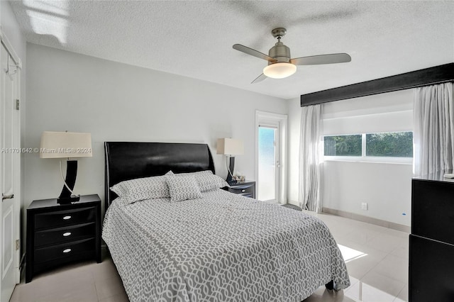 bedroom featuring ceiling fan, light tile patterned floors, and a textured ceiling