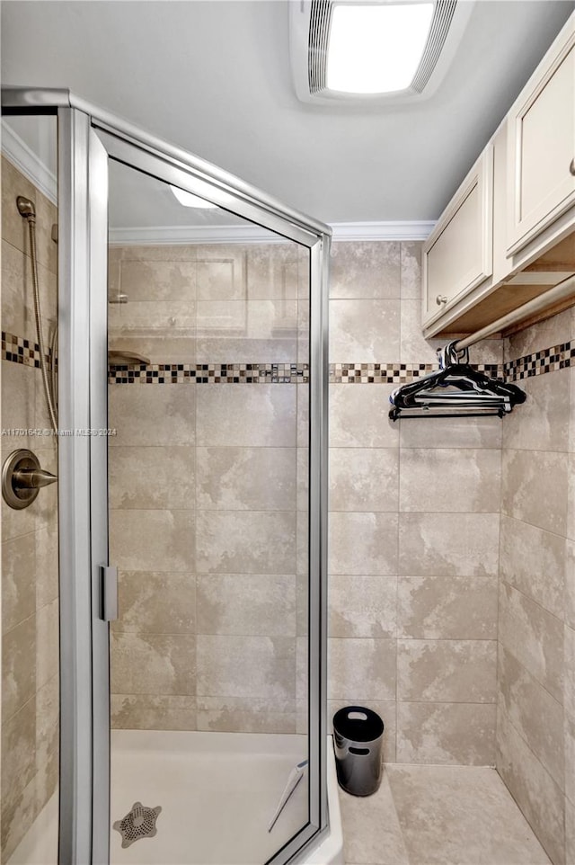 bathroom featuring crown molding and a shower with shower door