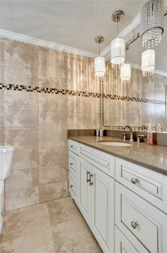 bathroom with a chandelier, toilet, vanity, tile walls, and ornamental molding