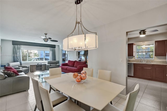 dining space featuring ceiling fan with notable chandelier, light tile patterned floors, and sink