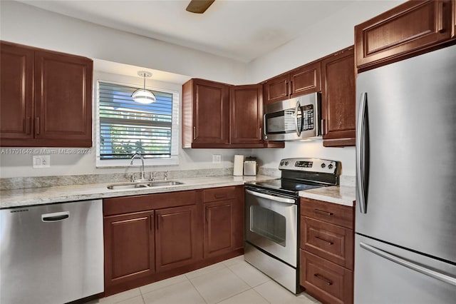 kitchen featuring pendant lighting, sink, light tile patterned floors, light stone counters, and stainless steel appliances