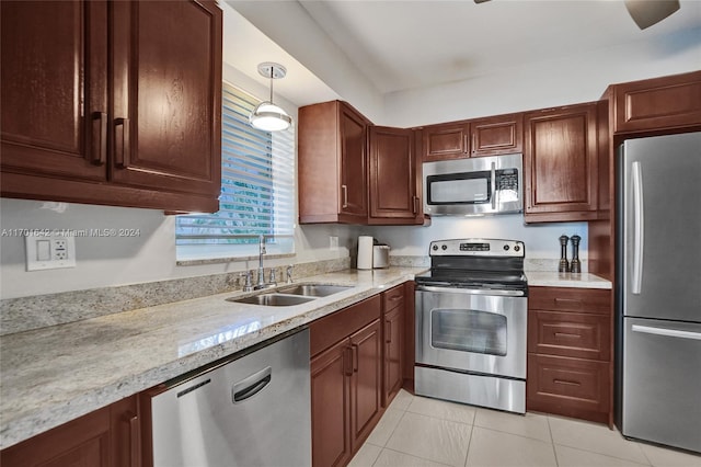 kitchen featuring sink, hanging light fixtures, light tile patterned floors, appliances with stainless steel finishes, and light stone counters