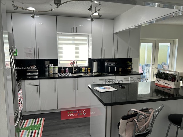 kitchen with stainless steel refrigerator, sink, white cabinets, and a textured ceiling