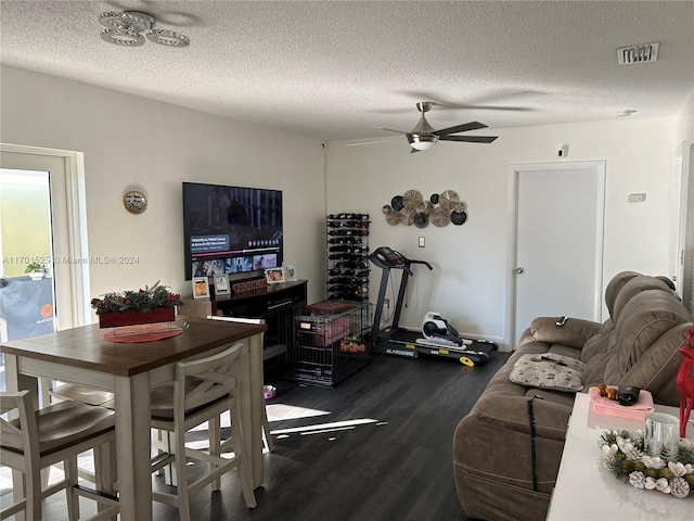 living room with ceiling fan, dark hardwood / wood-style flooring, and a textured ceiling