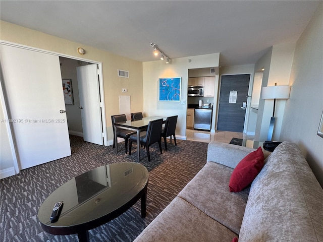 carpeted living room featuring track lighting, visible vents, and baseboards