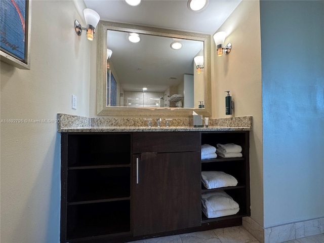 bathroom featuring a tile shower, vanity, and baseboards