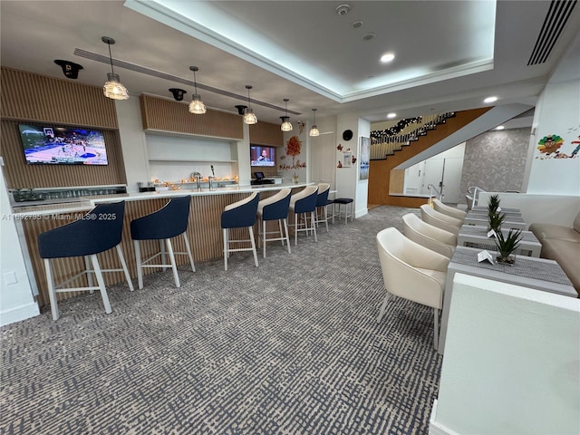 bar featuring pendant lighting, dark carpet, and a tray ceiling