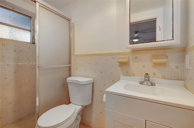 bathroom featuring walk in shower, vanity, toilet, and tile walls