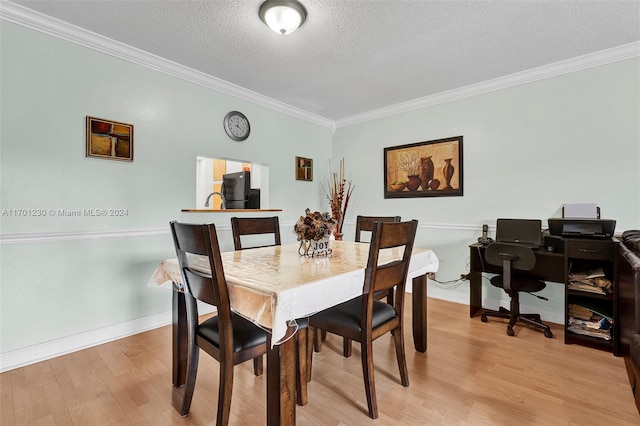 dining room with light wood-type flooring, a textured ceiling, and ornamental molding