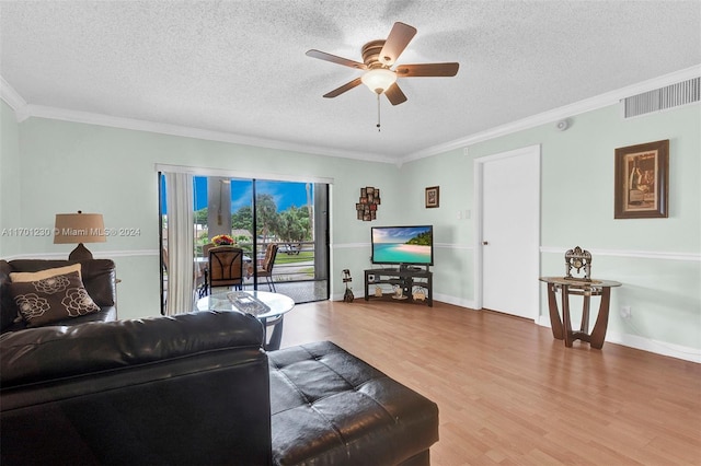 living room with wood-type flooring, a textured ceiling, ceiling fan, and ornamental molding