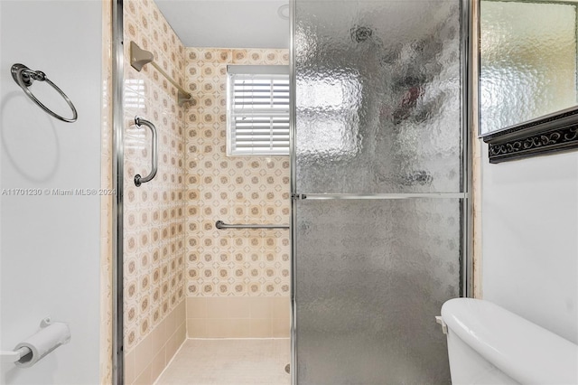 bathroom featuring toilet and a shower with shower door