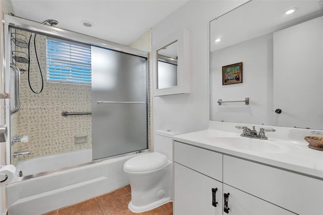 full bathroom with shower / bath combination with glass door, tile patterned flooring, vanity, and toilet