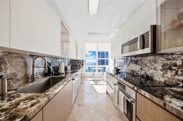 kitchen featuring decorative backsplash, modern cabinets, stainless steel appliances, stone counters, and a sink