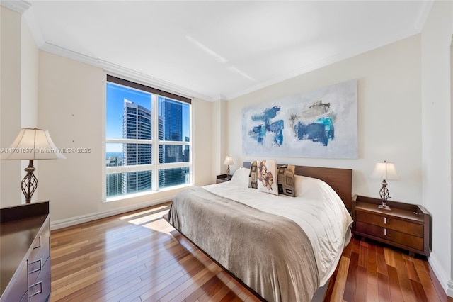 bedroom with ornamental molding, wood-type flooring, and baseboards