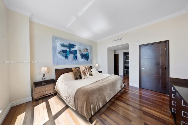 bedroom featuring ornamental molding, wood-type flooring, visible vents, and baseboards