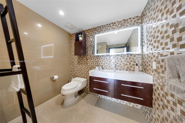 bathroom featuring toilet, tile patterned flooring, tile walls, and vanity